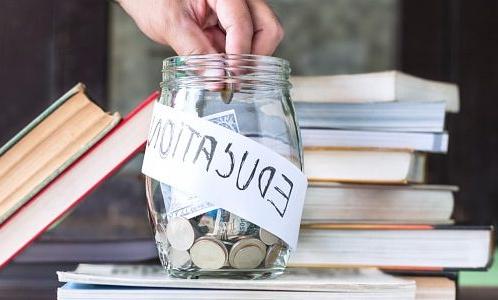 Coins and banknote in a glass jar placed on the textbook. Concept money saving for education.